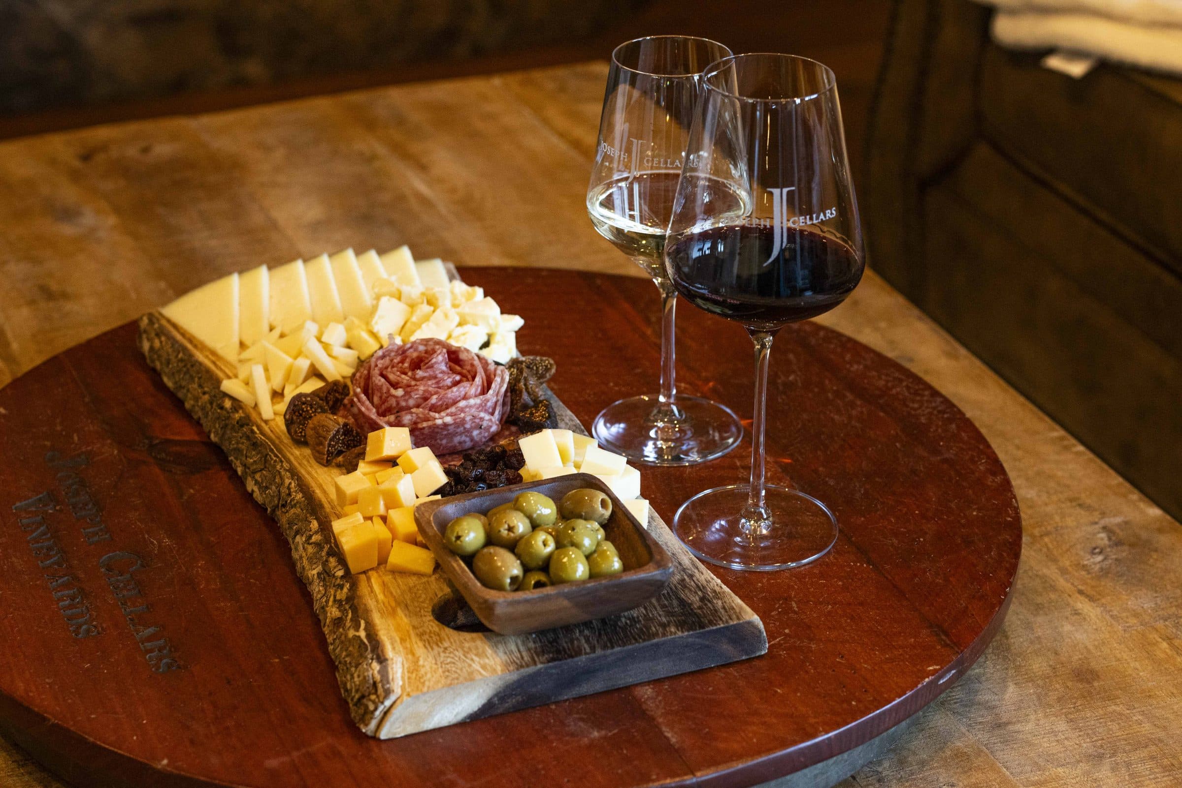 A cheese and charcuterie board with red and white wine at Joseph Cellars